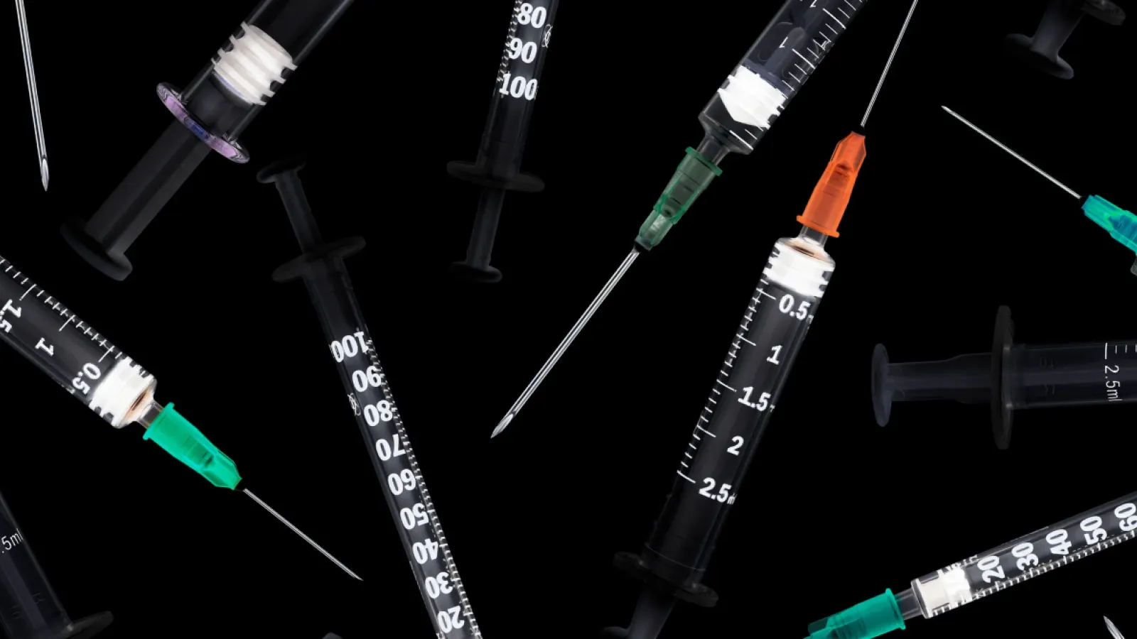 multiple syringes scattered on a black background